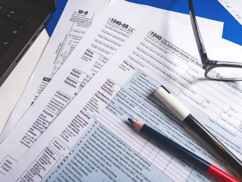 Tax documents stacked with pen and pencil